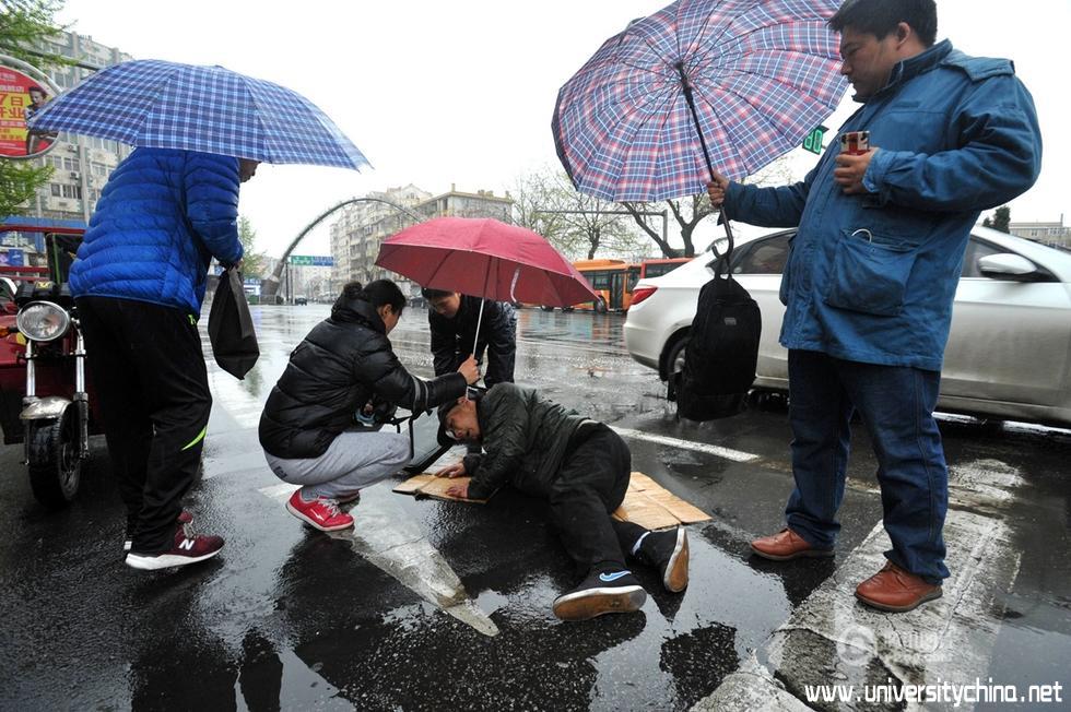 青岛一老人路上摔倒 众人雨中撑伞