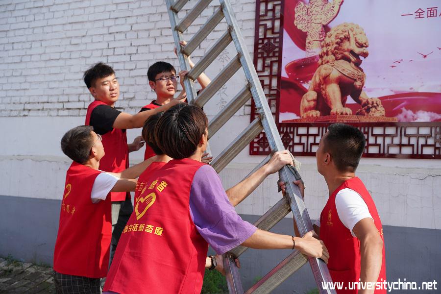 志愿者搬梯子清洗海报 中国青年网通讯员 何浩宇 摄.JPG