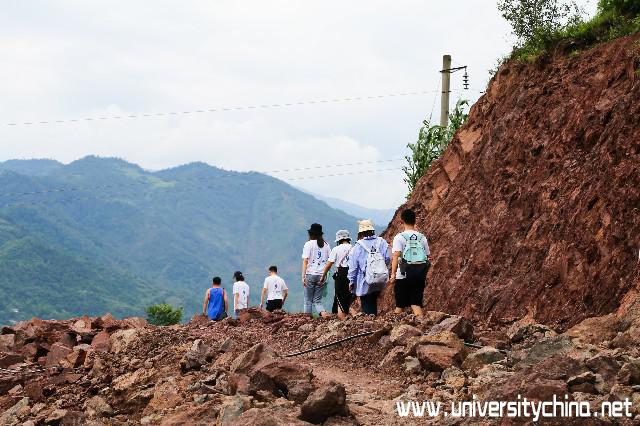 图为家访途中团队成员行走在泥泞的山路上.jpg